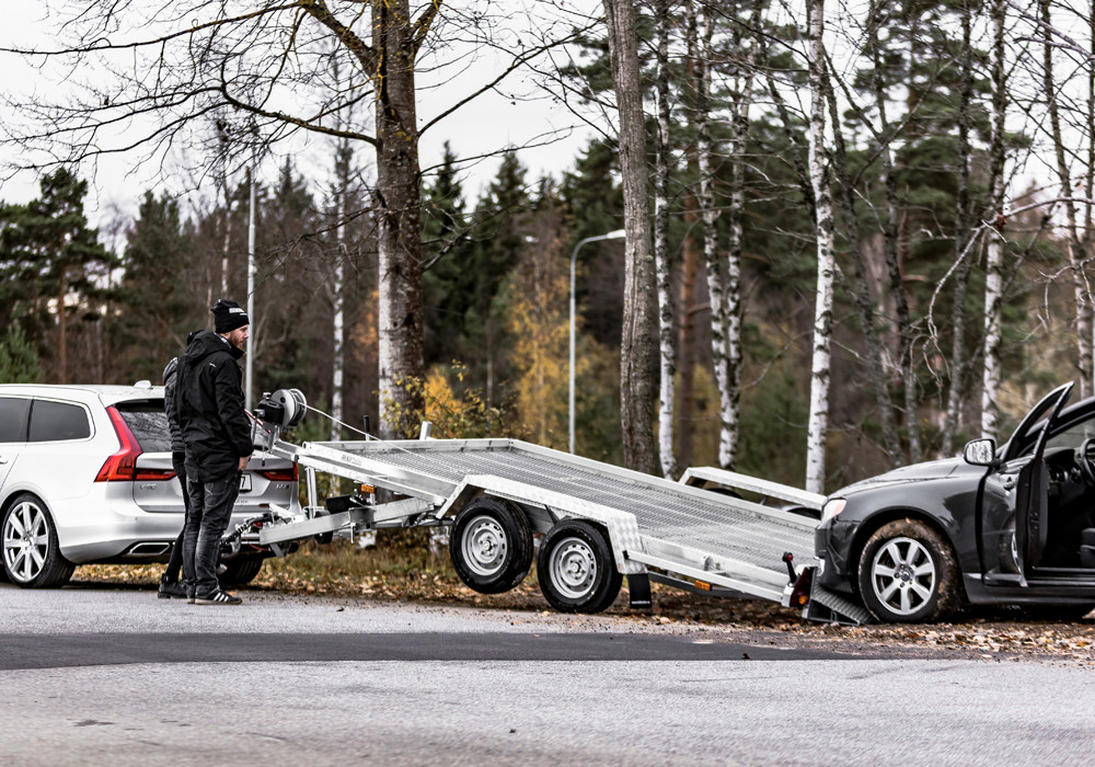 Bil som kör upp på ett bilsläp - ett fordonssläp gör transporten säker och smidig